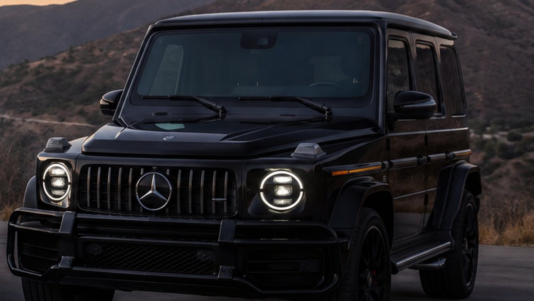 A black Mercedes-AMG G63 in the hills at sunset