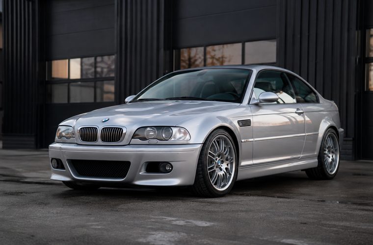 A silver BMW M3 outside a dark warehouse